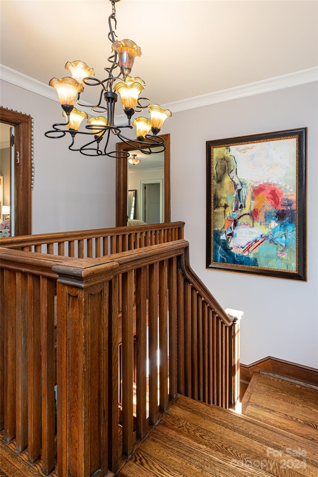 stairs featuring hardwood / wood-style flooring, a notable chandelier, and ornamental molding