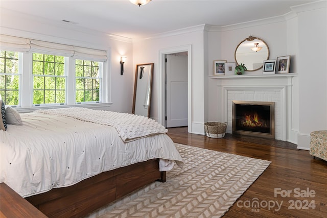 bedroom with dark hardwood / wood-style floors, ornamental molding, and a fireplace