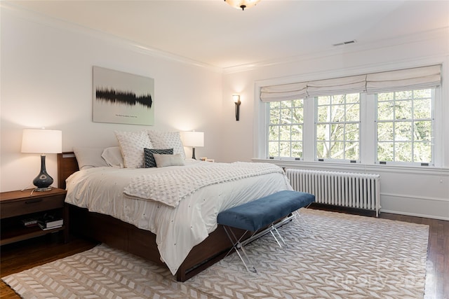 bedroom with radiator heating unit, hardwood / wood-style flooring, and ornamental molding