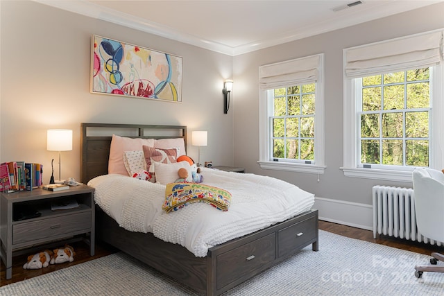 bedroom with hardwood / wood-style flooring, radiator, and crown molding