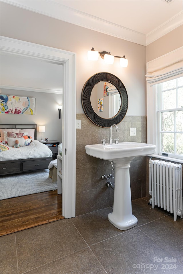 bathroom featuring radiator, ornamental molding, and tile walls