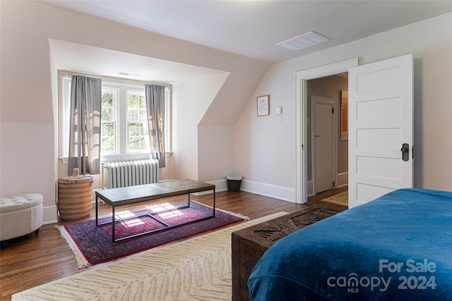 bedroom with vaulted ceiling, radiator, and dark hardwood / wood-style floors