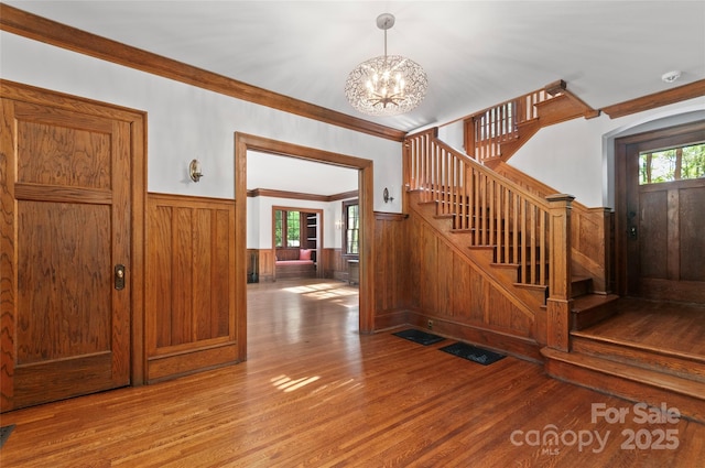 30 Cedarcliff Rd, Asheville, NC 28803 - stairs featuring wainscoting, wood finished floors, a chandelier, ornamental molding, and wood walls