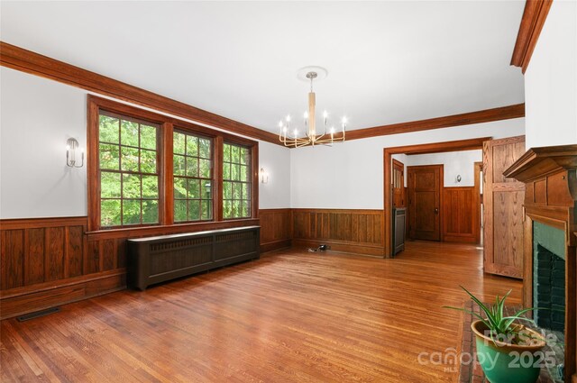 30 Cedarcliff Rd, Asheville, NC 28803 - unfurnished dining area with a wainscoted wall, radiator heating unit, a chandelier, wood finished floors, and a fireplace with flush hearth