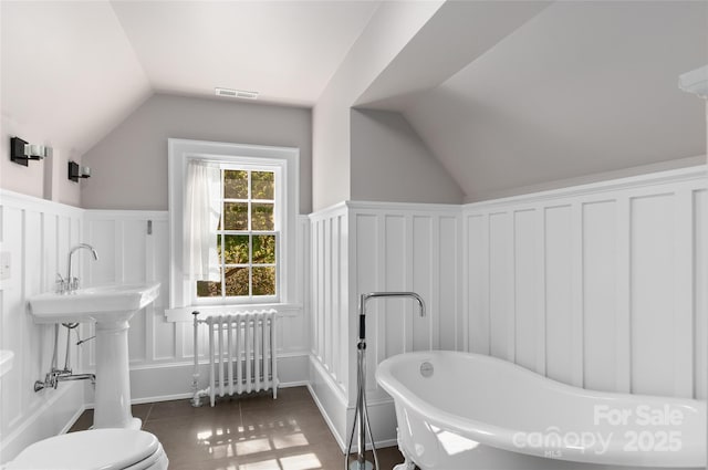 30 Cedarcliff Rd, Asheville, NC 28803 - bathroom with radiator, a decorative wall, vaulted ceiling, a freestanding tub, and toilet