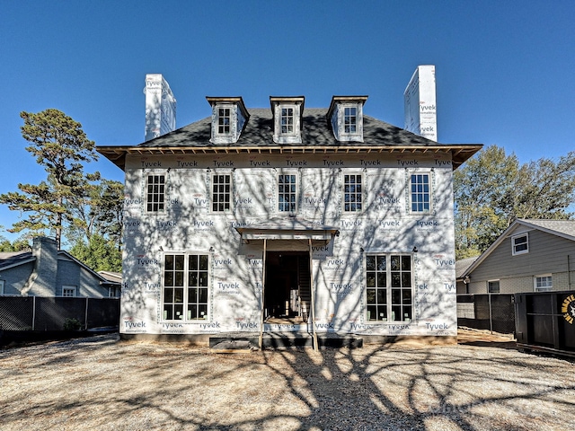 rear view of property featuring a chimney and fence