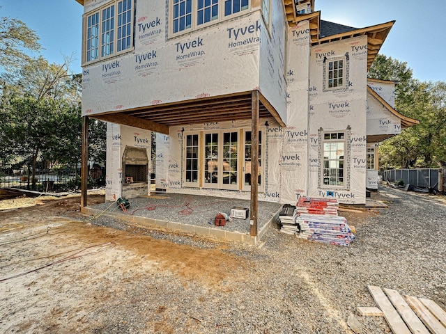 rear view of house featuring a fireplace, fence, and french doors