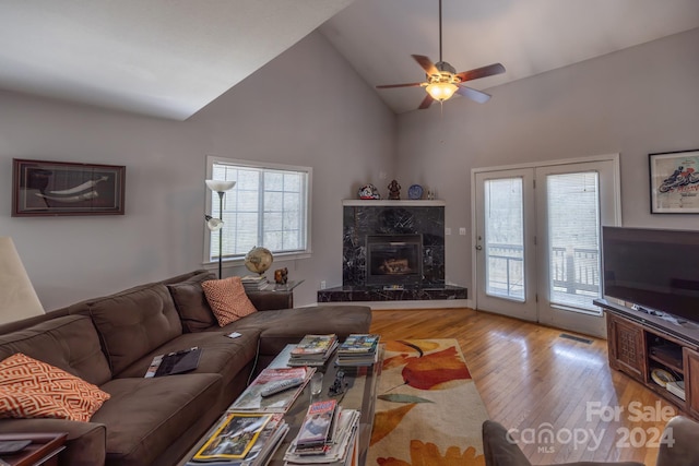 living room with high vaulted ceiling, light hardwood / wood-style flooring, a fireplace, and ceiling fan