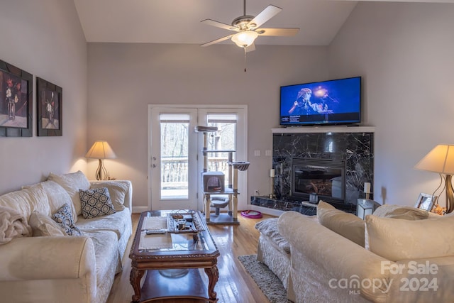 living room with hardwood / wood-style flooring, a high end fireplace, ceiling fan, and lofted ceiling