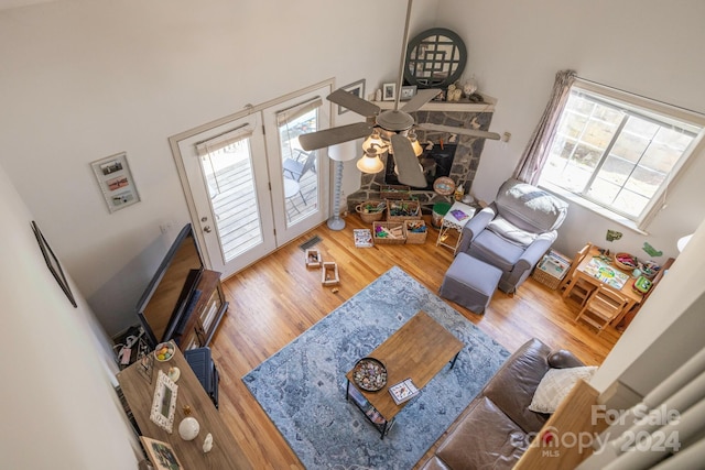 living room featuring wood-type flooring, ceiling fan, and a towering ceiling