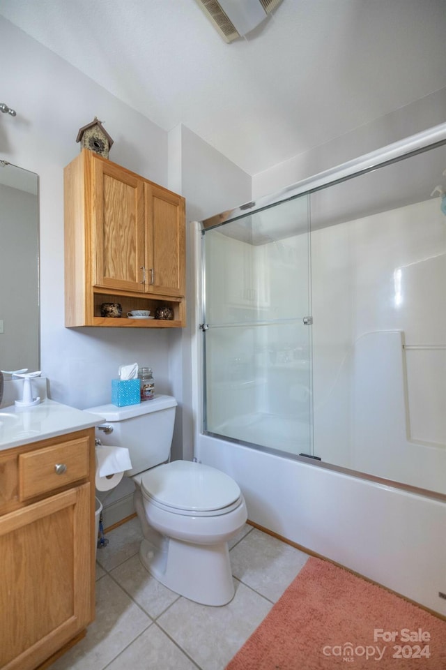 full bathroom featuring combined bath / shower with glass door, toilet, vanity with extensive cabinet space, and tile flooring