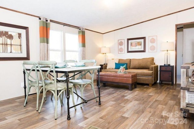 dining space with crown molding and light wood-type flooring