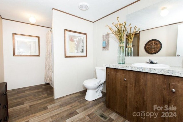 bathroom with vanity, ornamental molding, toilet, and wood-type flooring