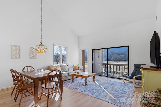 living room featuring an inviting chandelier, high vaulted ceiling, and light hardwood / wood-style floors