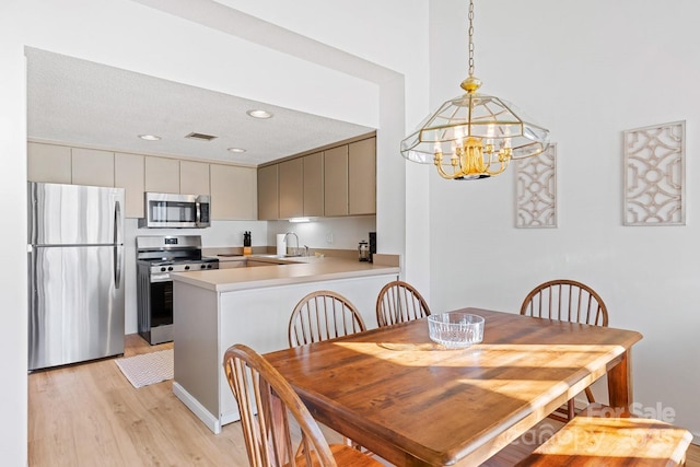 dining area with sink, a notable chandelier, a textured ceiling, and light hardwood / wood-style flooring