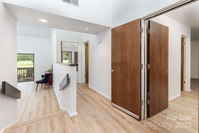 hall featuring light hardwood / wood-style floors and a textured ceiling