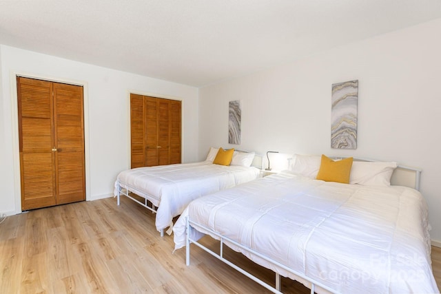 bedroom with two closets and light wood-type flooring