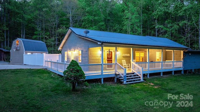 view of front of house with a front yard, an outdoor structure, and covered porch