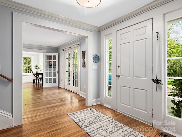 entrance foyer with hardwood / wood-style floors, french doors, and ornamental molding