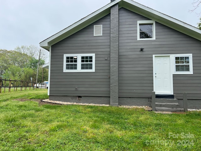 rear view of house featuring crawl space, a lawn, and fence