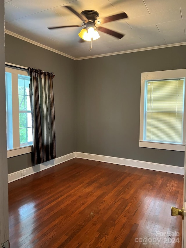 spare room with baseboards, ornamental molding, and dark wood-style flooring