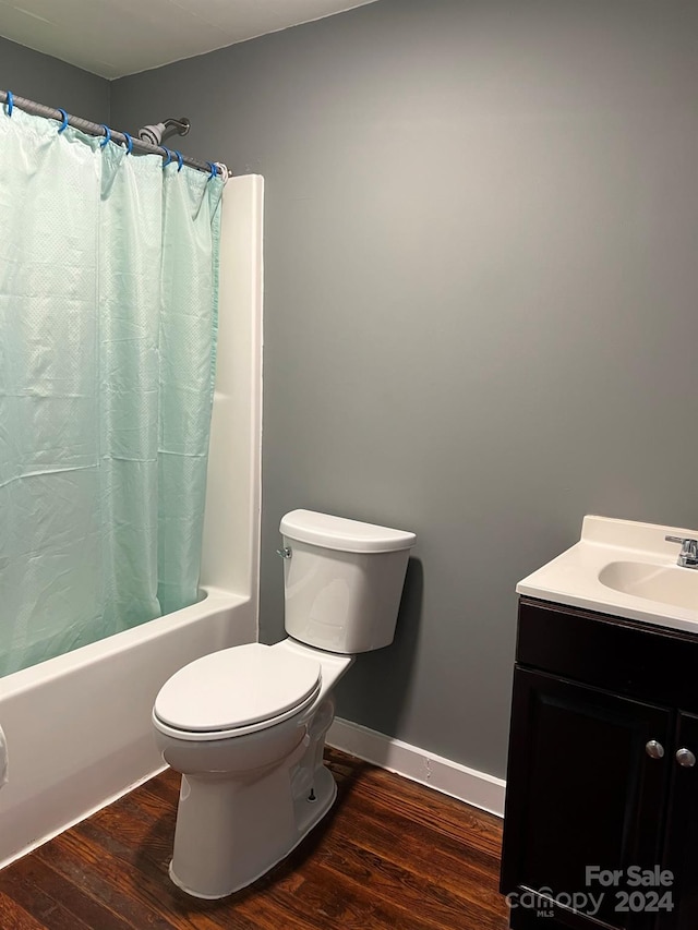 bathroom featuring baseboards, toilet, shower / bath combo with shower curtain, wood finished floors, and vanity