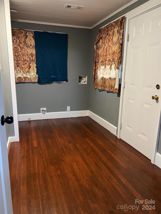 spare room with ornamental molding, wood finished floors, visible vents, and baseboards