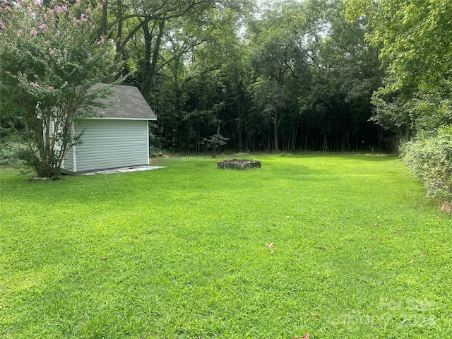 view of yard featuring an outbuilding, a storage unit, and a view of trees