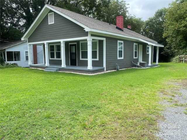 back of house with a porch, central AC, a lawn, a chimney, and driveway