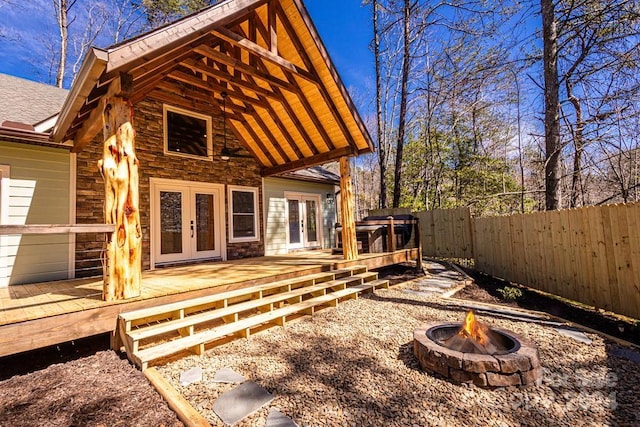 rear view of house featuring french doors, a deck, and an outdoor fire pit