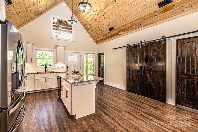 kitchen with a barn door, a kitchen island, high vaulted ceiling, wood ceiling, and stainless steel fridge