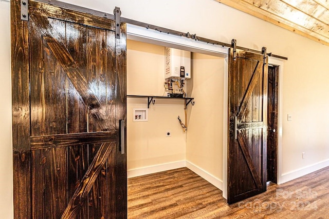 interior space featuring water heater, light hardwood / wood-style floors, and a barn door