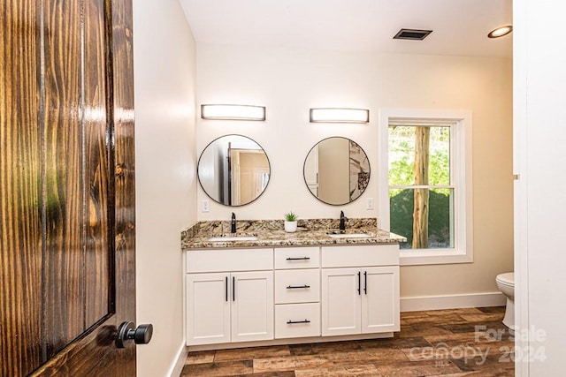 bathroom featuring double vanity, hardwood / wood-style flooring, and toilet