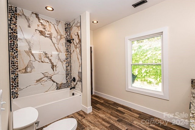 bathroom with wood-type flooring, tiled shower / bath combo, and toilet