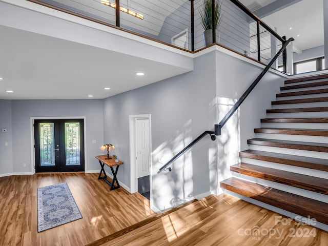 entryway with french doors, hardwood / wood-style floors, and a high ceiling