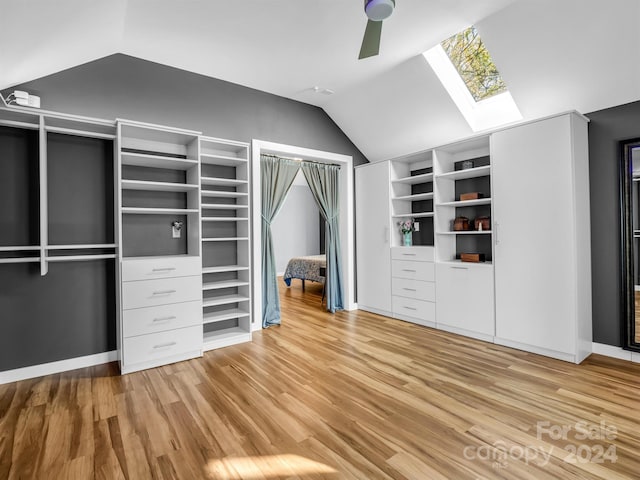 spacious closet with ceiling fan, lofted ceiling with skylight, and light hardwood / wood-style floors