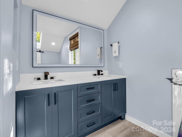 bathroom featuring vanity, lofted ceiling with skylight, and hardwood / wood-style flooring