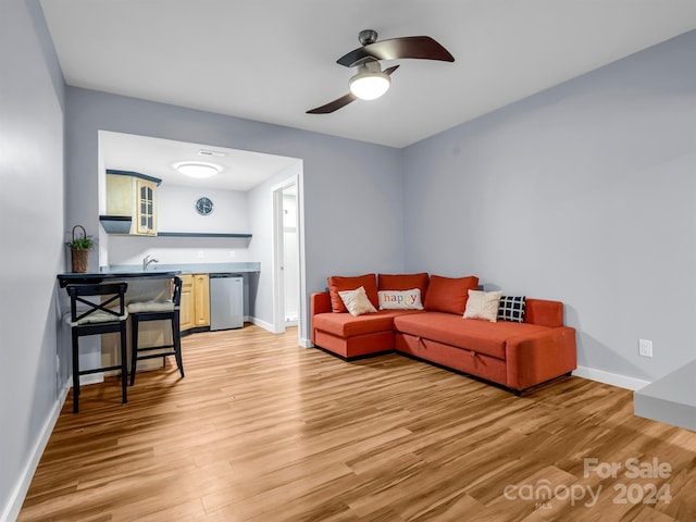 living room featuring light wood-type flooring, ceiling fan, and sink