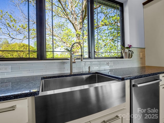room details featuring white cabinetry, decorative backsplash, and a sink