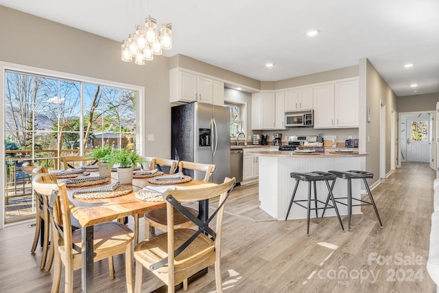 dining space with light hardwood / wood-style floors and a notable chandelier