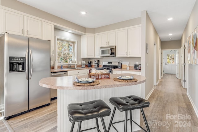 kitchen featuring a kitchen breakfast bar, a center island, light hardwood / wood-style floors, and stainless steel appliances