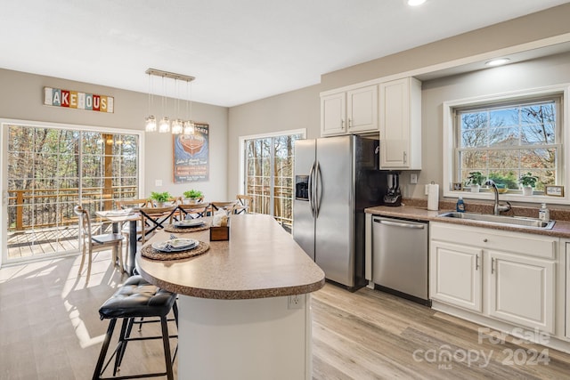 kitchen with a wealth of natural light, sink, white cabinets, and appliances with stainless steel finishes