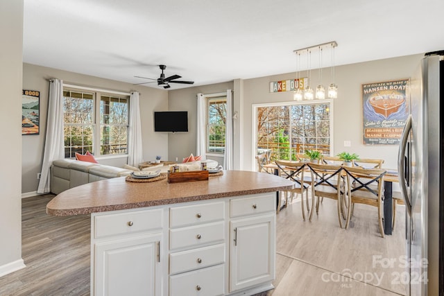 kitchen featuring decorative light fixtures, a center island, white cabinetry, and stainless steel refrigerator