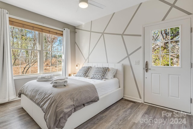 bedroom with wood-type flooring, multiple windows, and ceiling fan