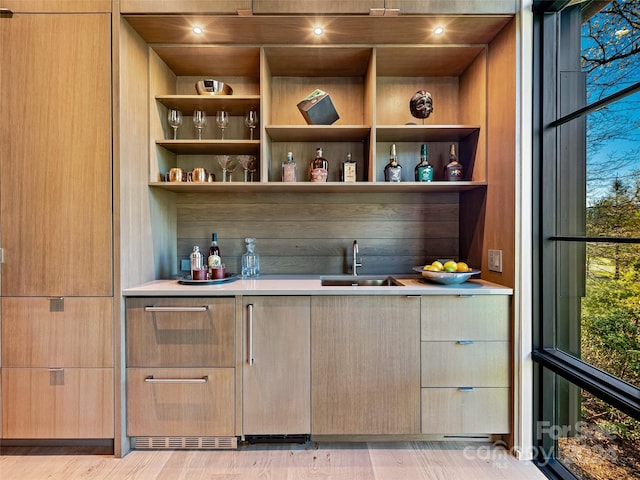 bar featuring a wealth of natural light, light hardwood / wood-style floors, and sink