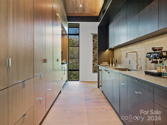 bar with light stone countertops, light hardwood / wood-style flooring, sink, wood ceiling, and tasteful backsplash