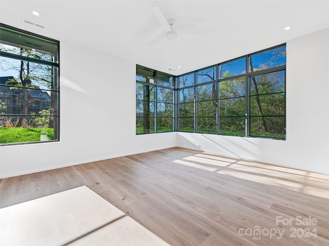 spare room with light hardwood / wood-style floors, ceiling fan, and expansive windows