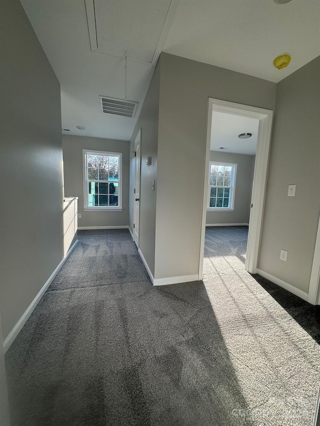 corridor with a wealth of natural light and dark carpet