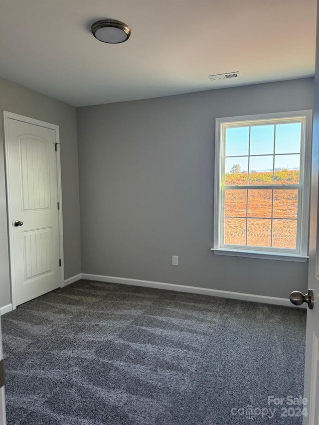 unfurnished room with dark colored carpet