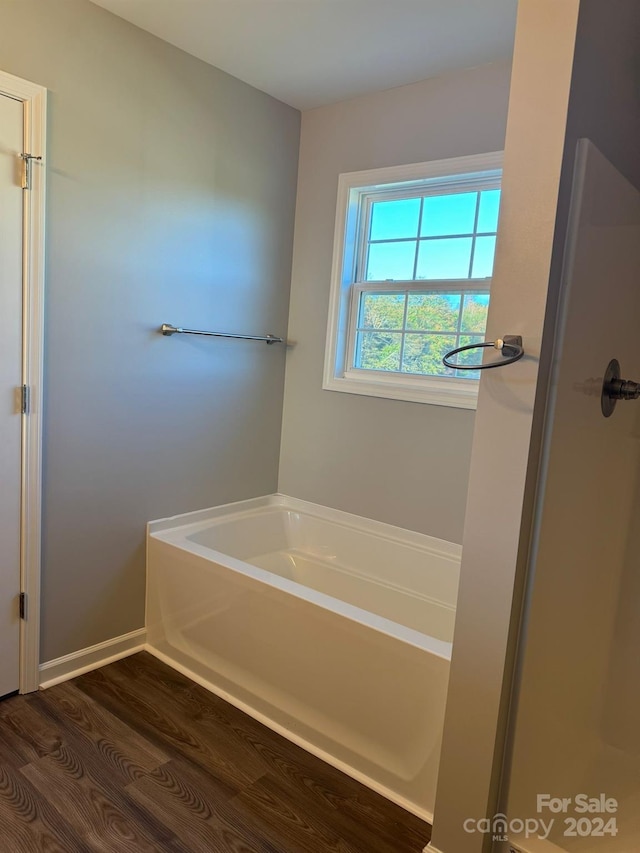 bathroom featuring wood-type flooring and a tub to relax in